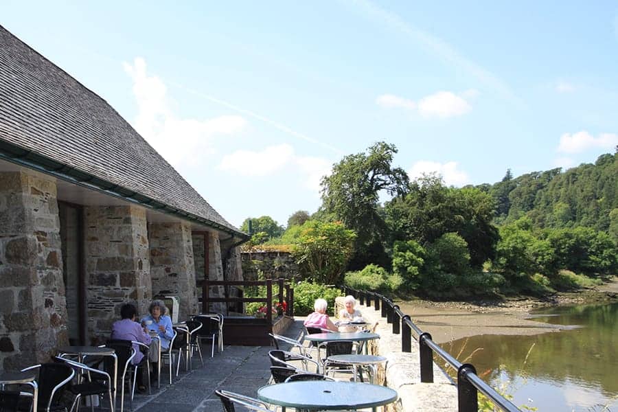 People sat outside Lopwell Dam Cafe overlooking River Tavy