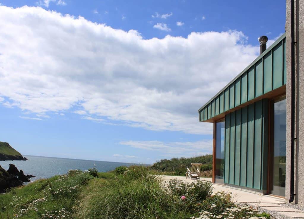 Contemporary garden room protruding from large renovated house out to sea