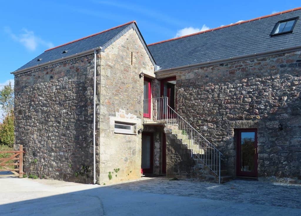 Dartmoor Granite Barn Conversion with steps leading up to red door, Moor Farm