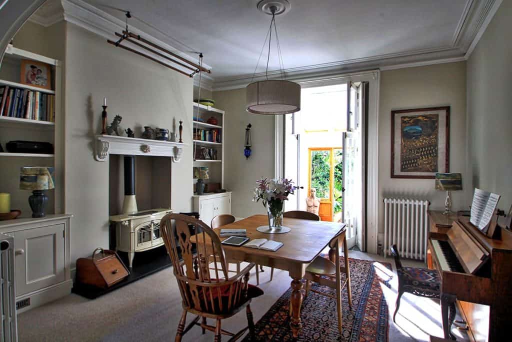 Large dining area of Georgian Townhouse with high ceilings, white log burner and piano